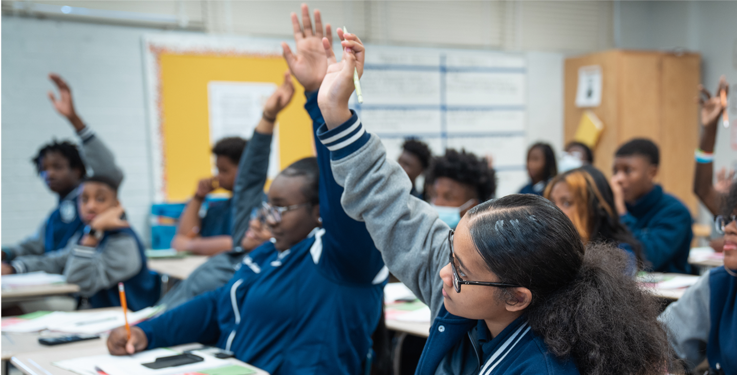 students in class raising their hands