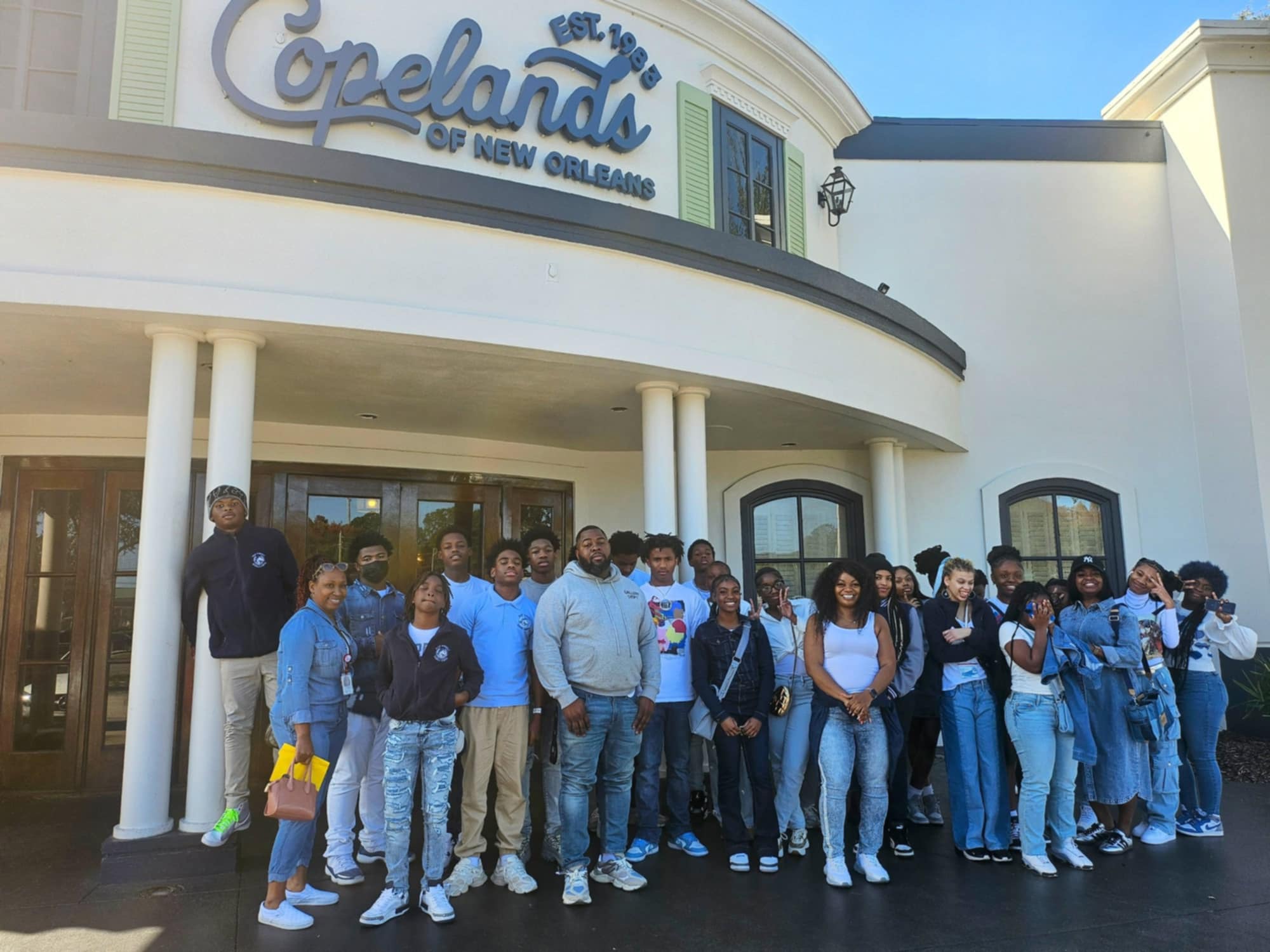 Group of people standing in front of the "Copeland's of New Orleans" restaurant entrance.