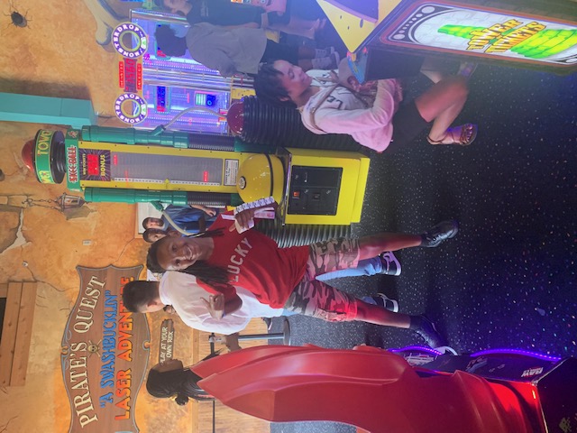 People in a game arcade, one person standing with a red shirt and a child crouching.
