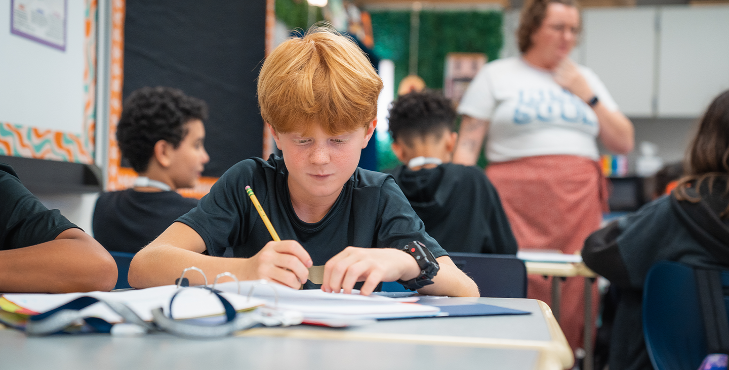 student in class writing in his notebook