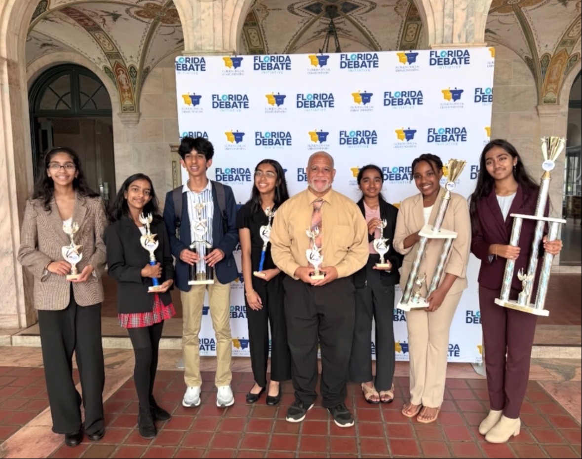 A group of individuals stand together, holding awards. A banner behind them displays multiple logos and text.