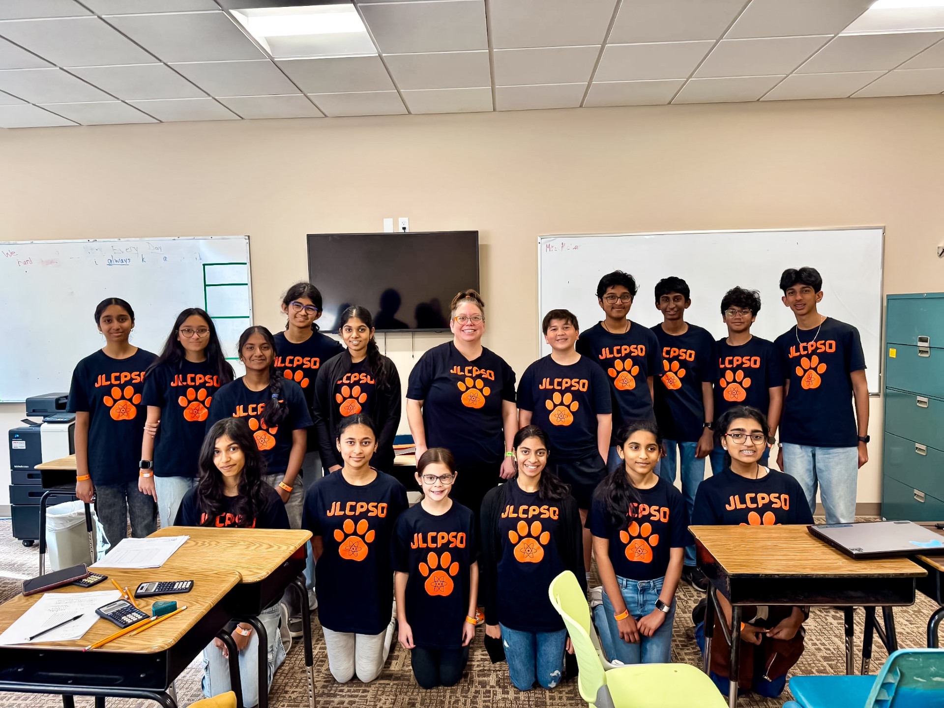 Group of students in matching blue t-shirts with paw prints in a classroom setting.