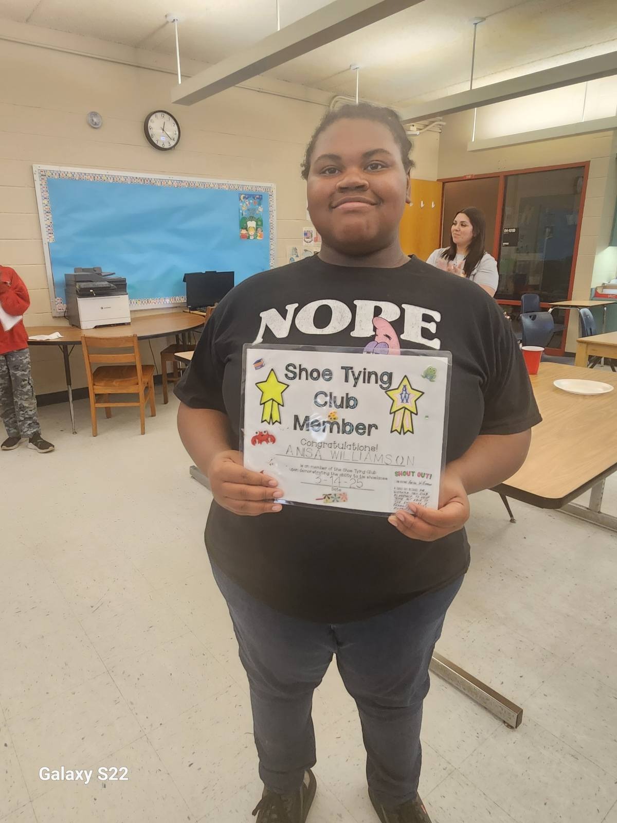 Anisa W. displaying her certificate for the students completing her shoe tying club.