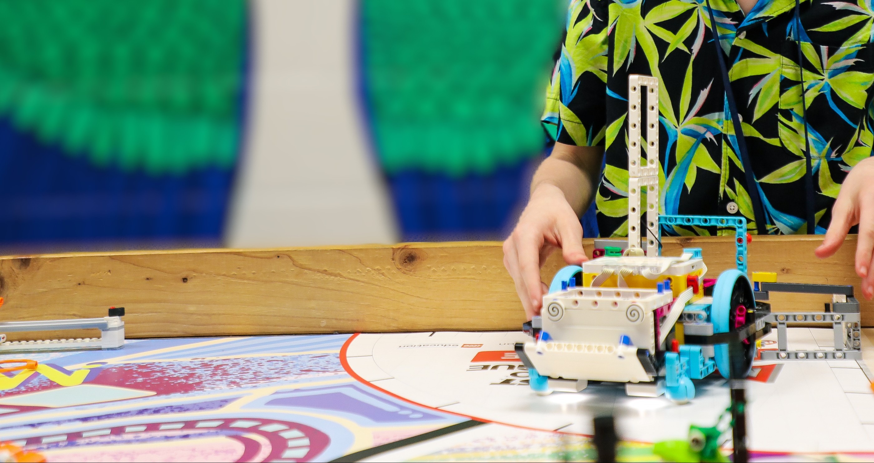 Detailed image of a robotics board with a lego robotic on the board.  There is a student behingd the board .
