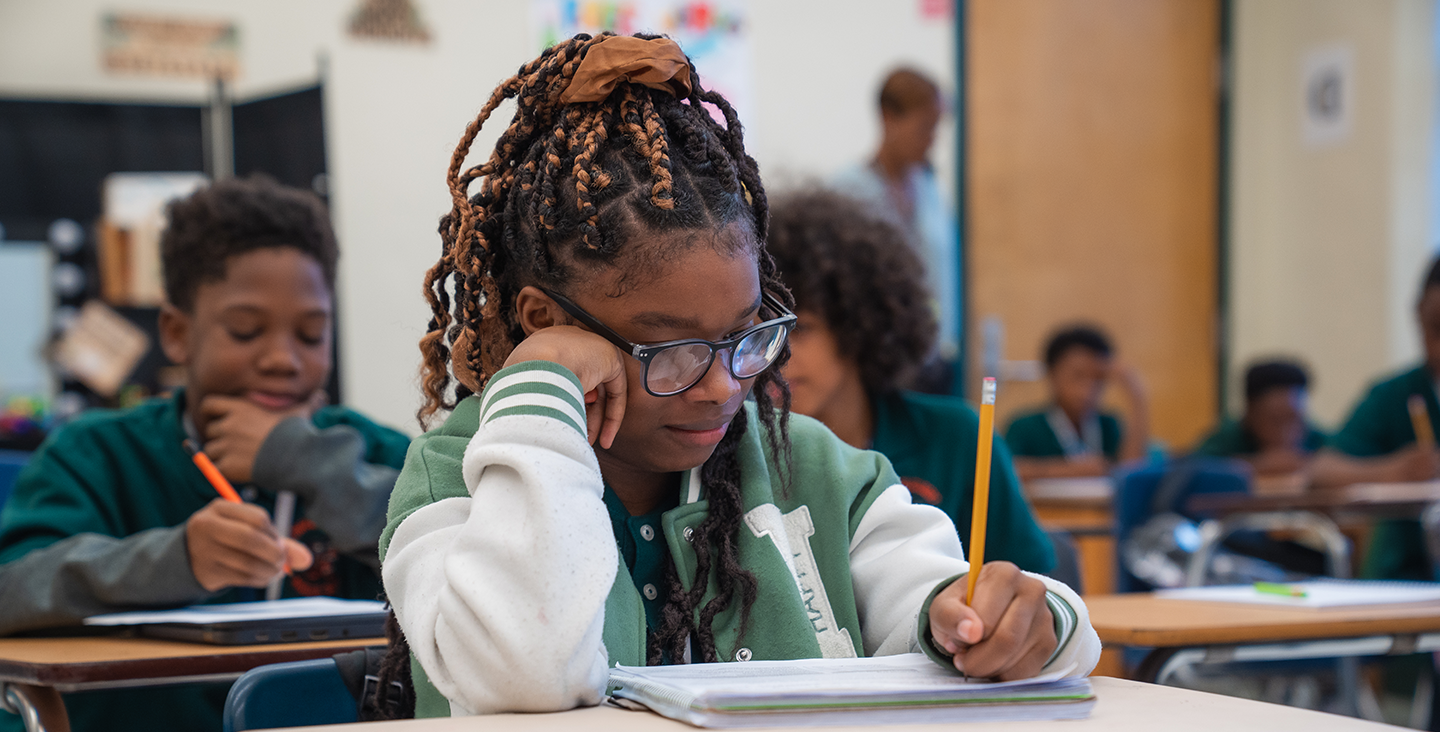 student at her desk writing in her notebook