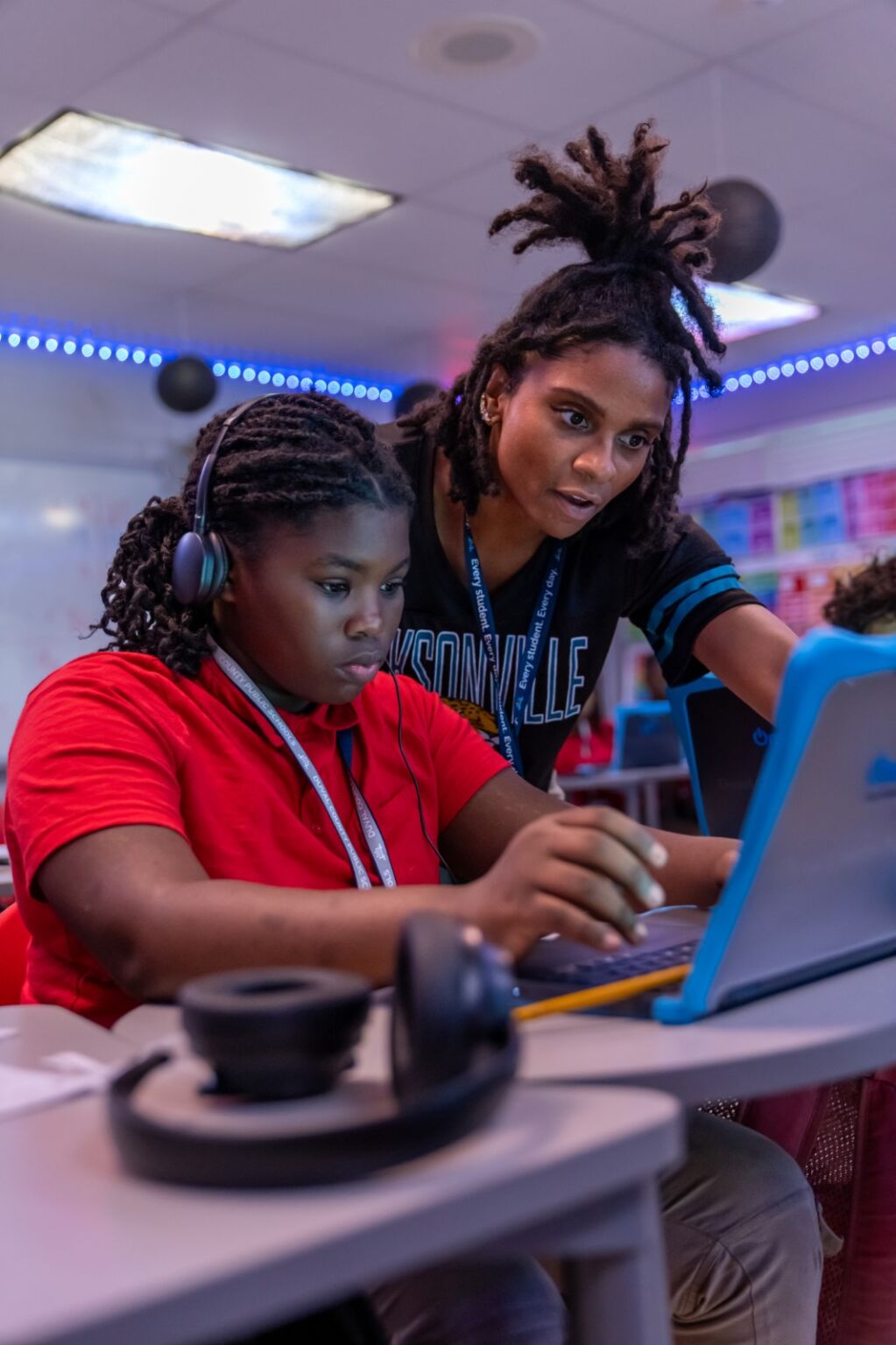 a teacher helping a student on a laptop