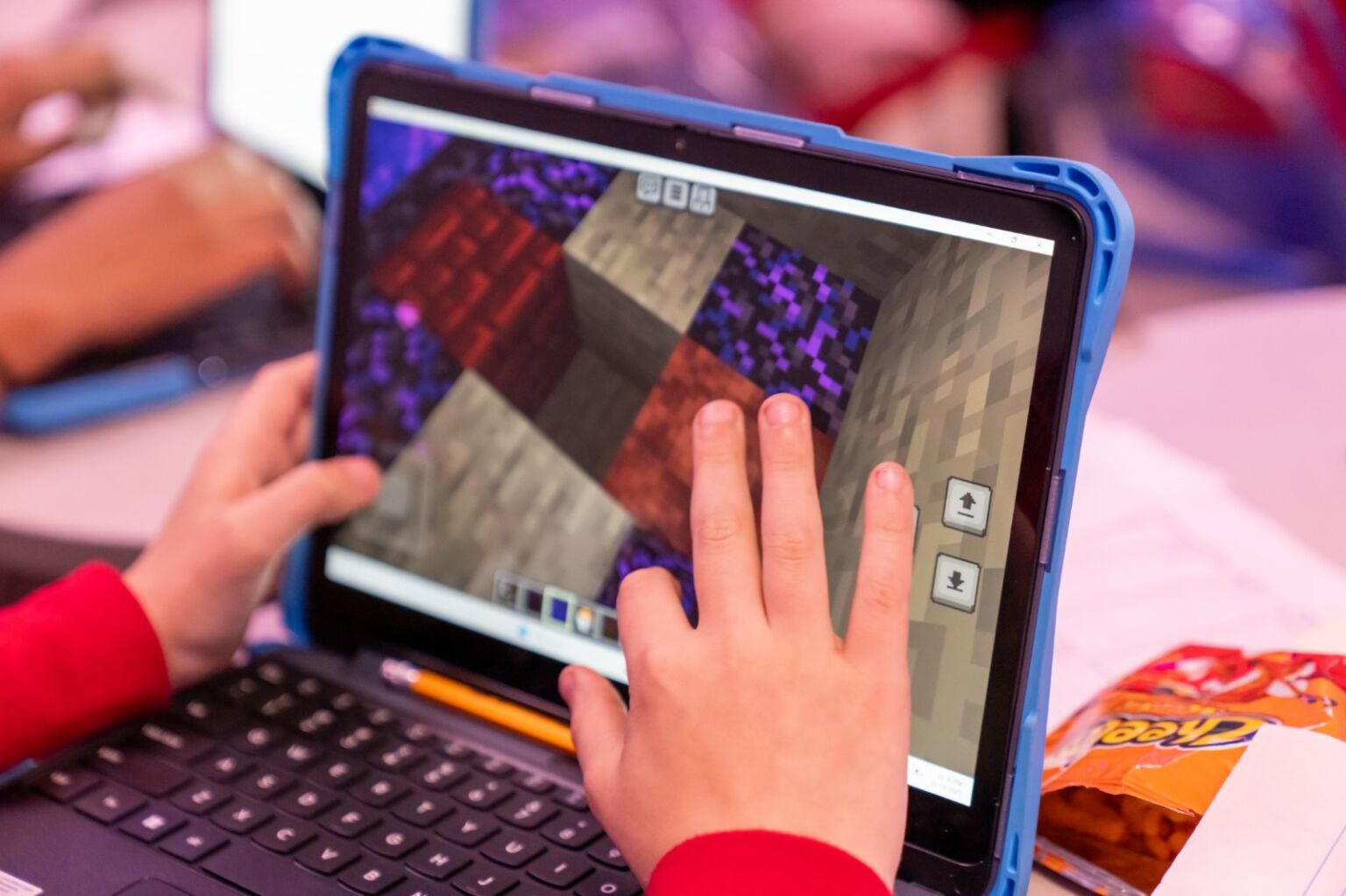 laptop screen with a student's hands playing Minecraft