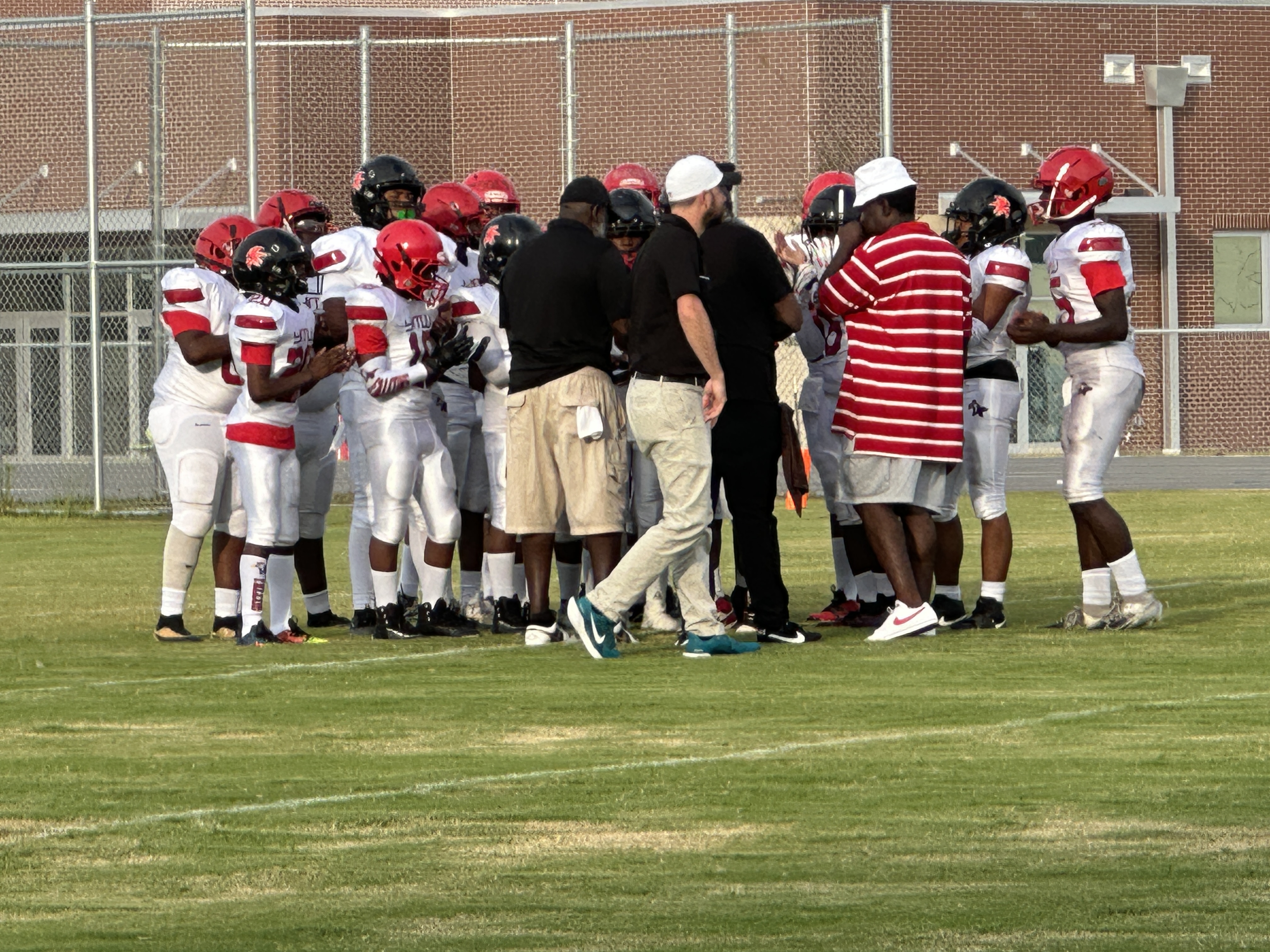 Football team huddled with the coaches on the field
