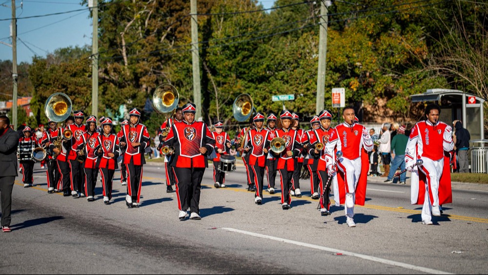 High school band in red and black uniforms.  The band is in line formation.