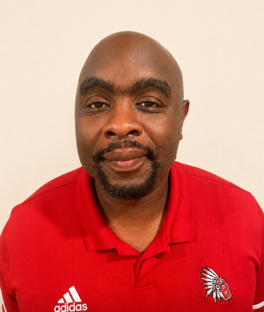 A man with a beard, wearing a red Adidas polo shirt with a logo on the left chest area.