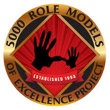A circular emblem with "5000 ROLE MODELS OF EXCELLENCE PROJECT" at the top. It features two hands, one larger than the other, interlocking.
