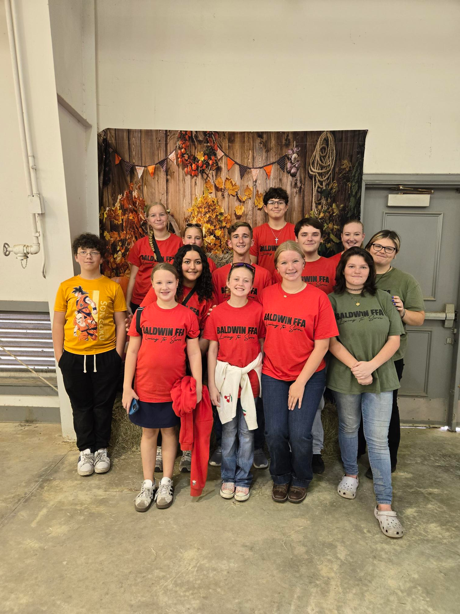 Group of children in matching shirts posing in a room with a wooden backdrop.