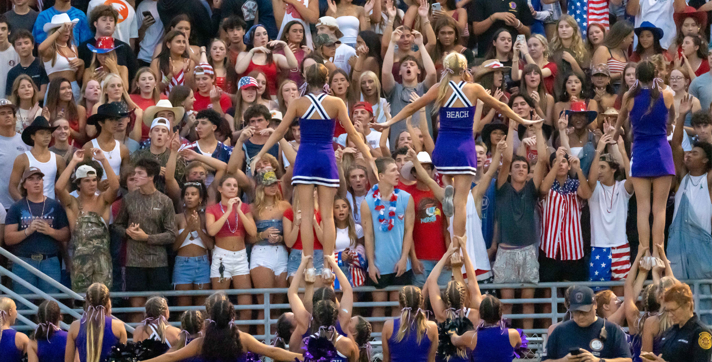 Cheerleaders cheering in front of stadium crowd