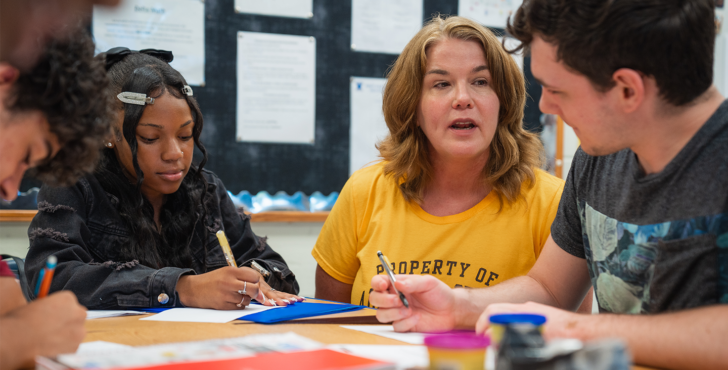 Teacher sitting at table with classroom students