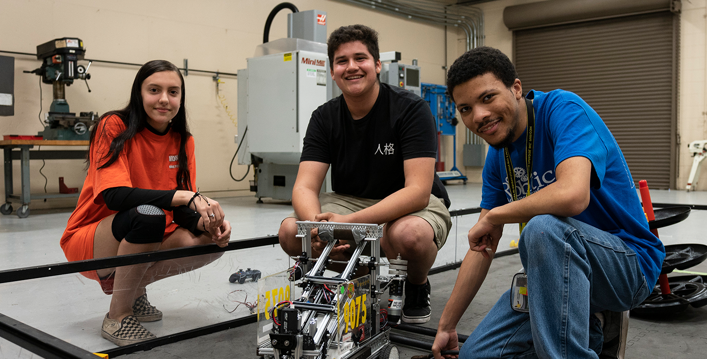 students smiling with robotic machine 