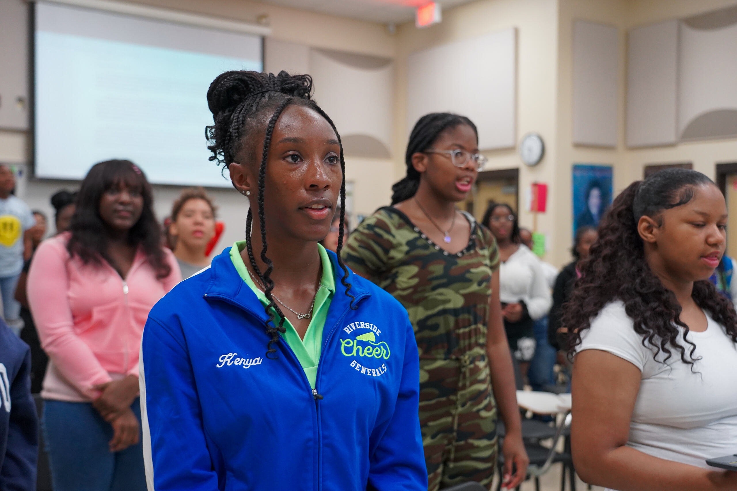 Student standing up wearing a cheer jacket