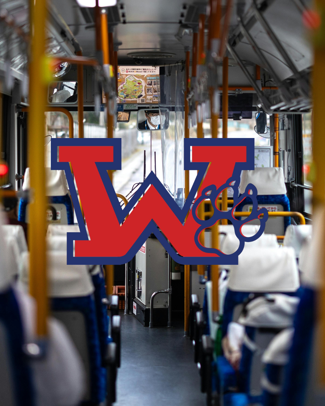 Interior of a bus with empty blue and gray seats and a red "W" logo in front.
