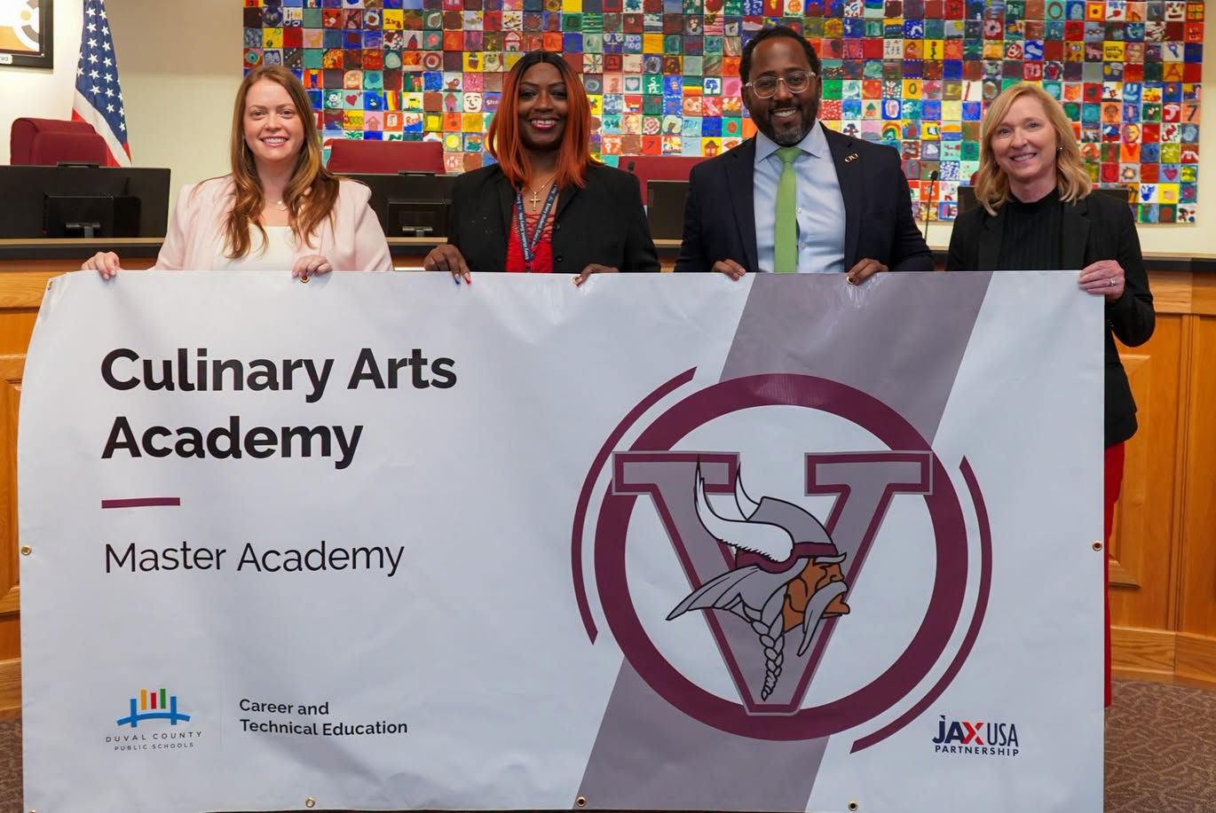 Four adults hold a banner with the words "Culinary Arts Academy" and "Master Academy" on it.