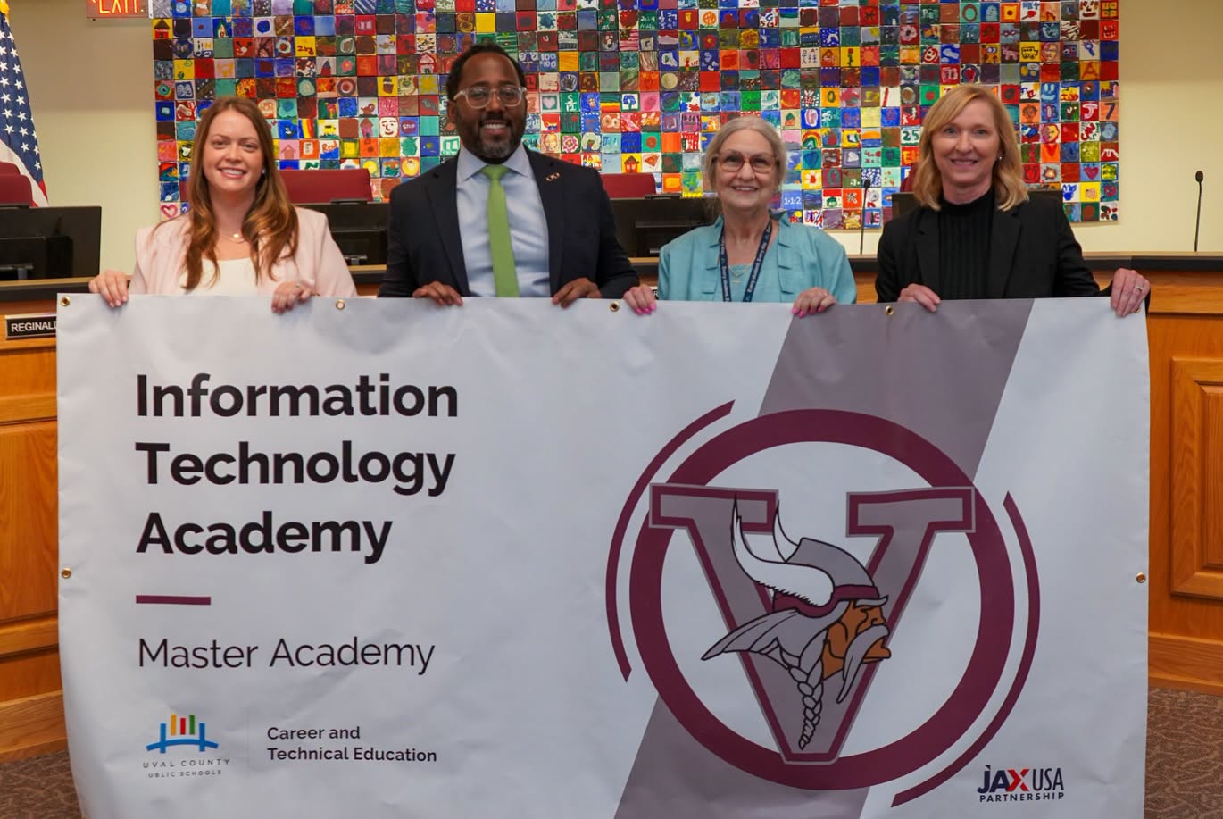 Four individuals standing behind a banner that reads "Information Technology Academy" with a logo.