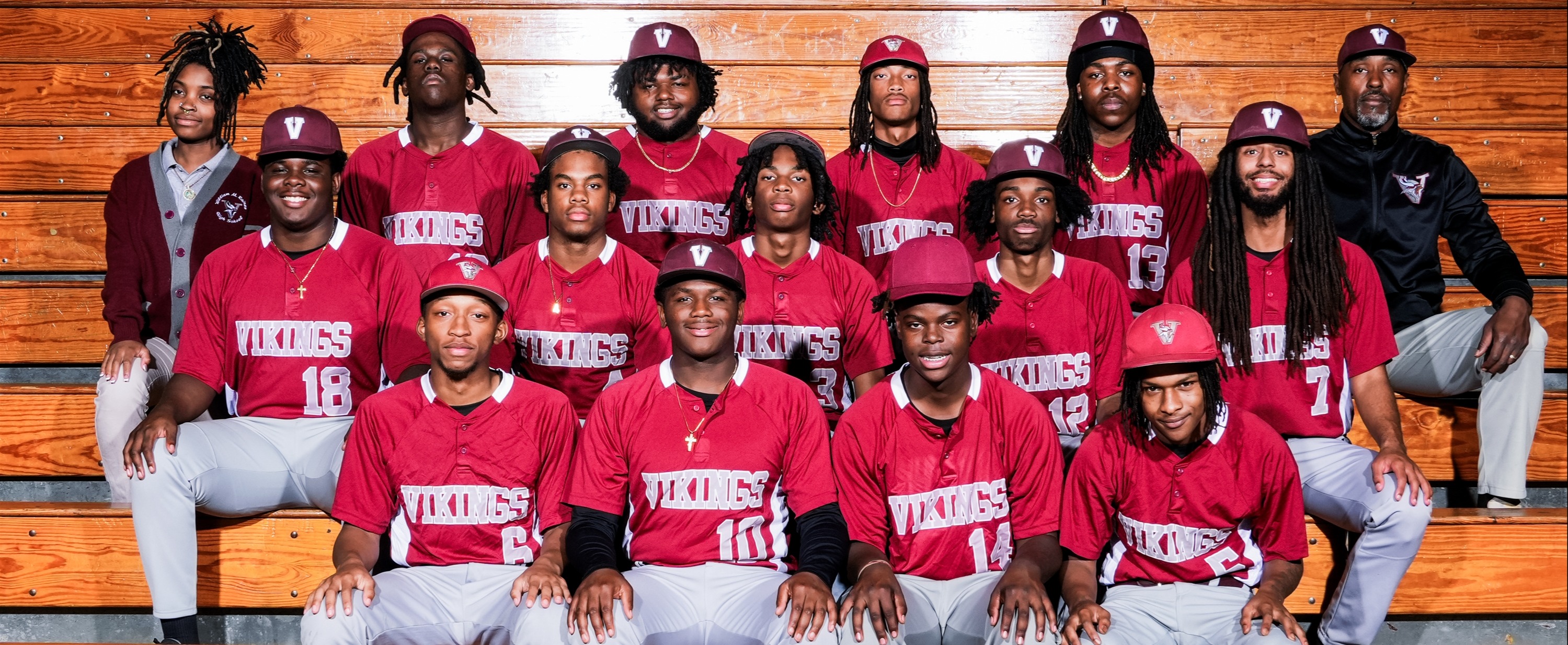 A sports team with matching uniforms poses in a stadium. The team wears red shirts, gray pants, and red caps.