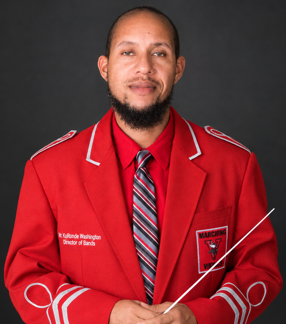 Man in red jacket, gray tie, and white baton in front of black background.