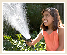 a girl sprays water into the air from a hose