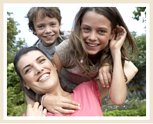 a boy, a girl, and an adult woman press in close to pose a for a photo