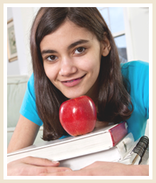 a girl rests her chin on top of an apple that sits on top of a pile of books