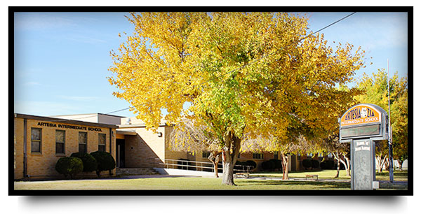 a large tree with yellow leaves in front of the entrance to Artesia Intermediate School