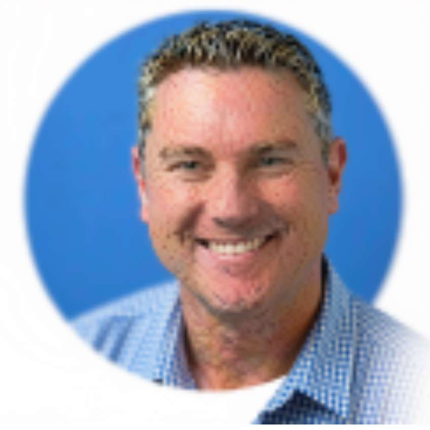 A smiling man with short, light-colored hair wears a blue shirt. He stands against a blue background.