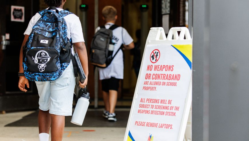 A student wearing a backpaclk walks into a school.