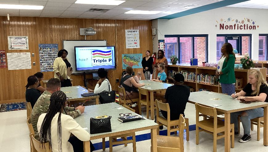 image of parents sitting at tables listening to a presenter