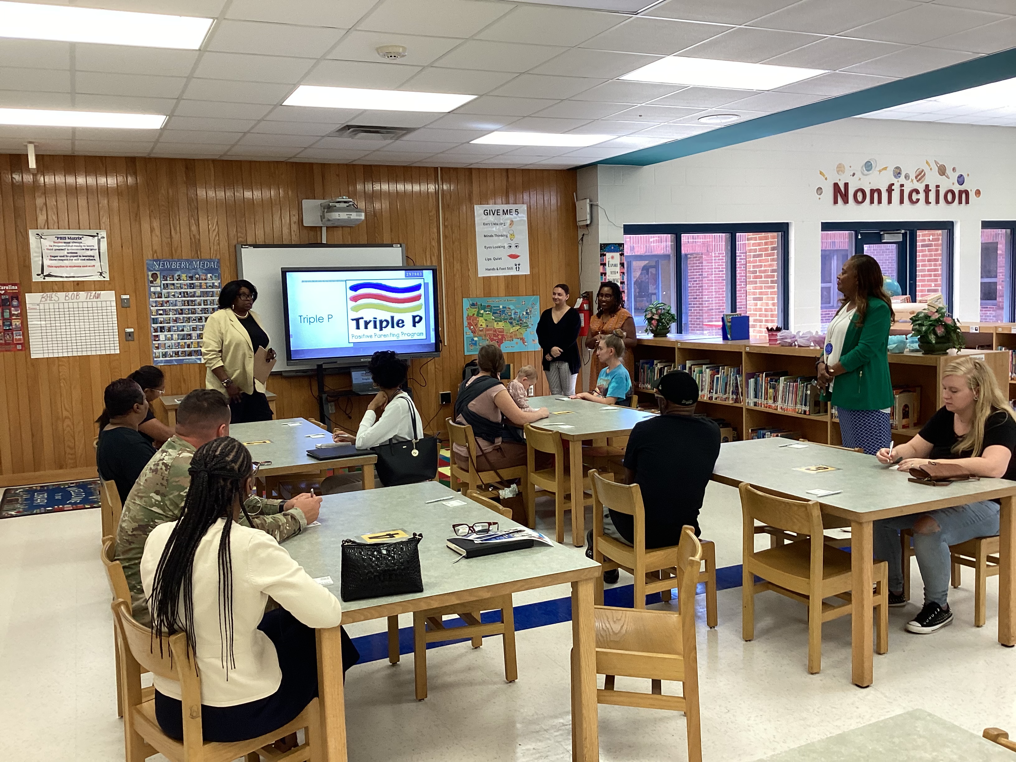 image of parents sitting at tables listening to a presenter