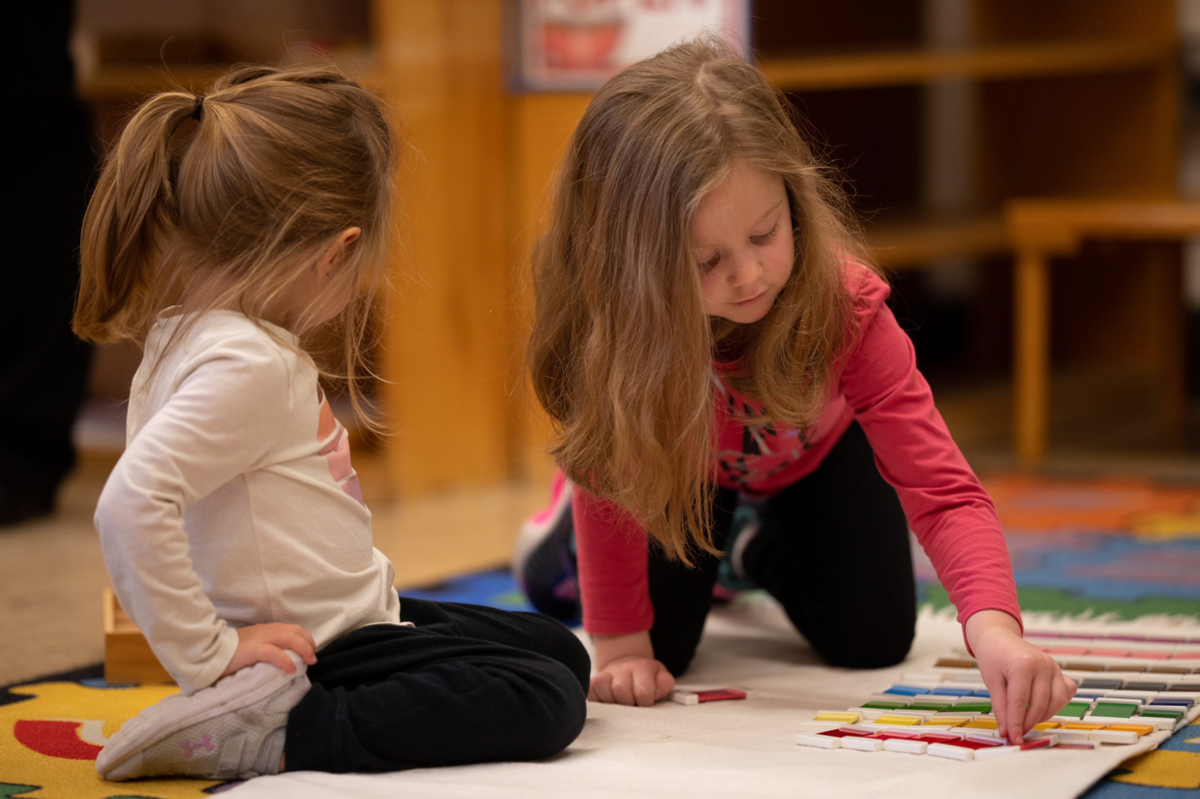 2 girls playing on floor.