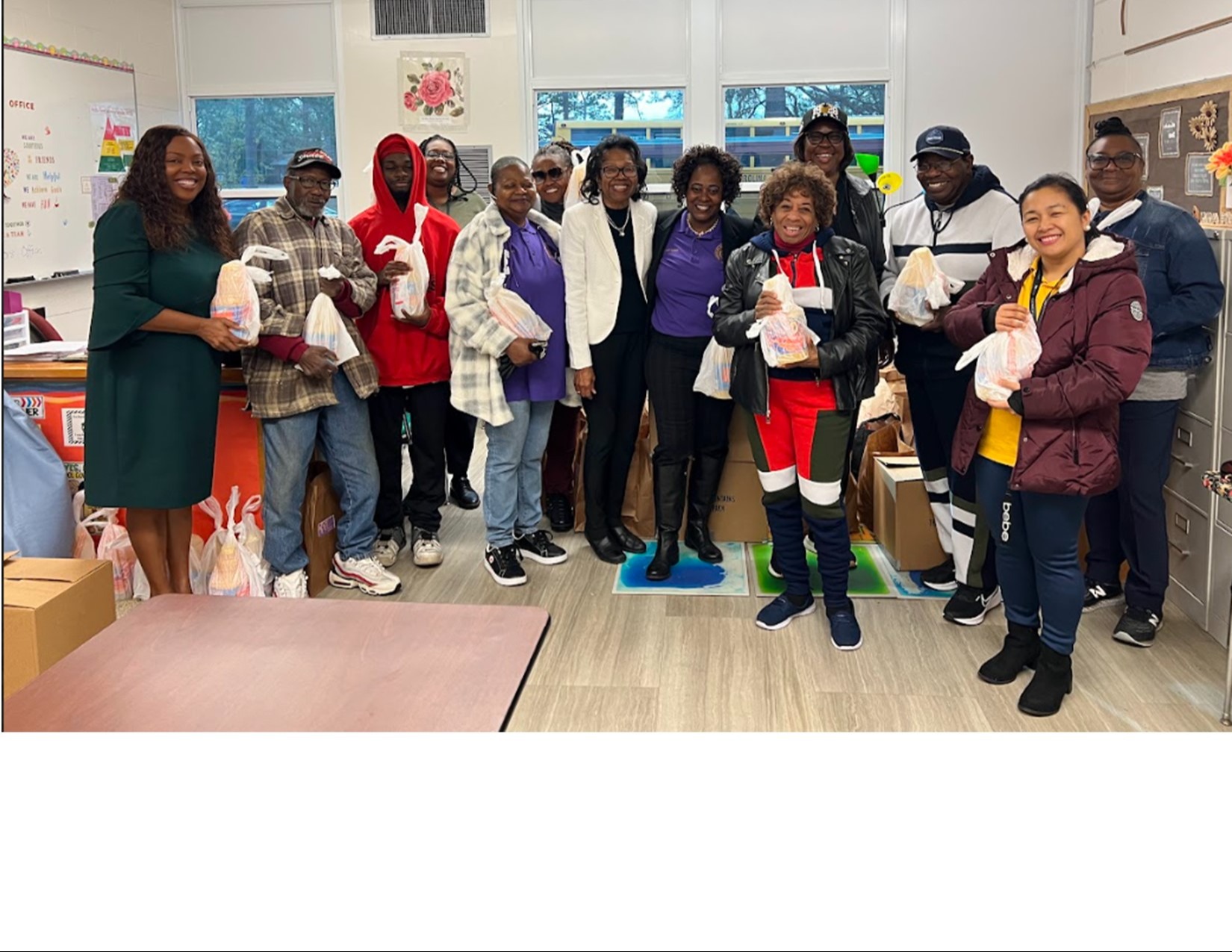 A picture of a group of 13 adults smiling and holding grocery bags .