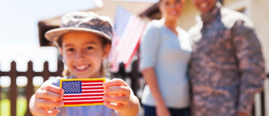 Image showing a child holding a flag patch with her veteran father and mother in the background