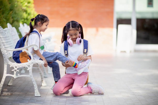 girl tying  another girl's shoes