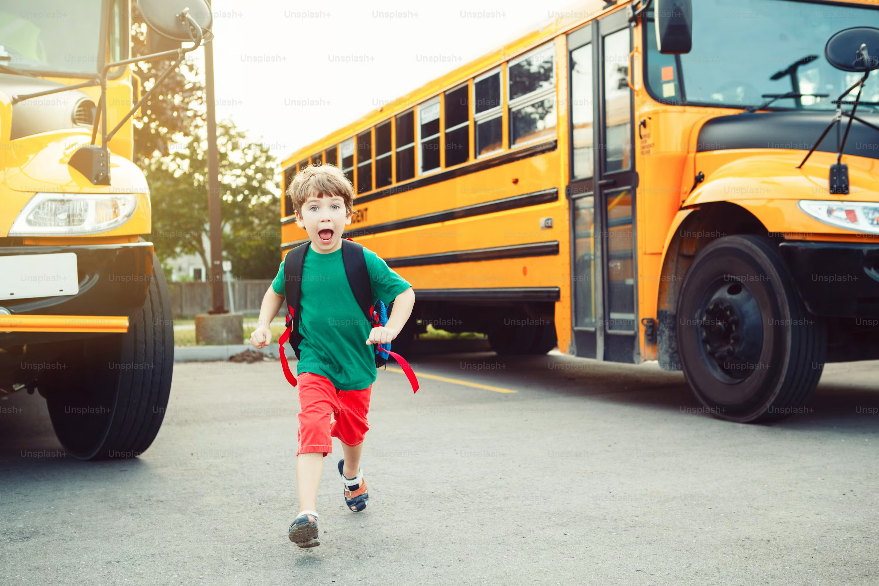 boy running by two school buses
