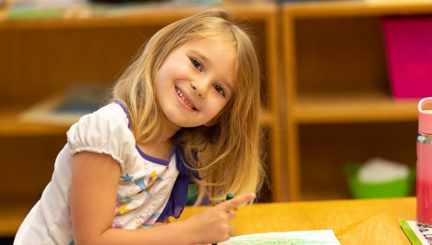 Child at desk smiling