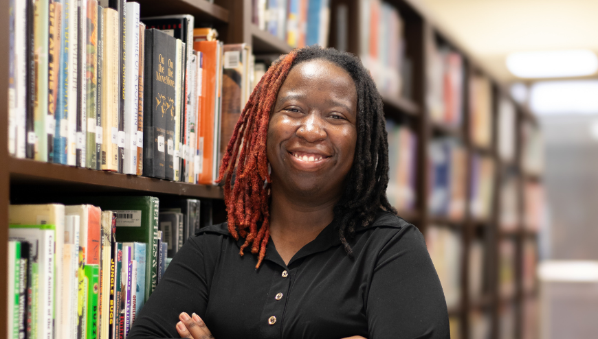 Student in media center leaning on shelves