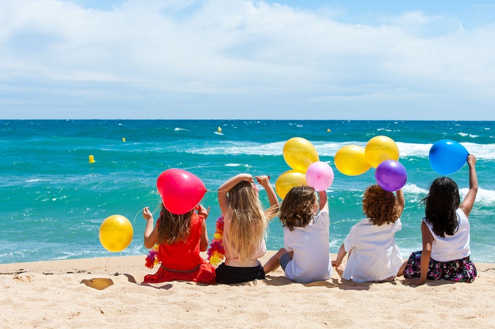 Children at beach holding ballons