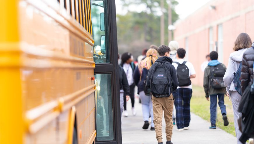  image of students walking by buses