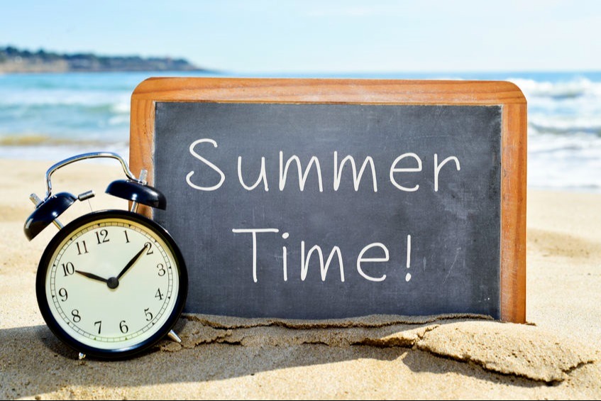 Clock in sand with water in the background