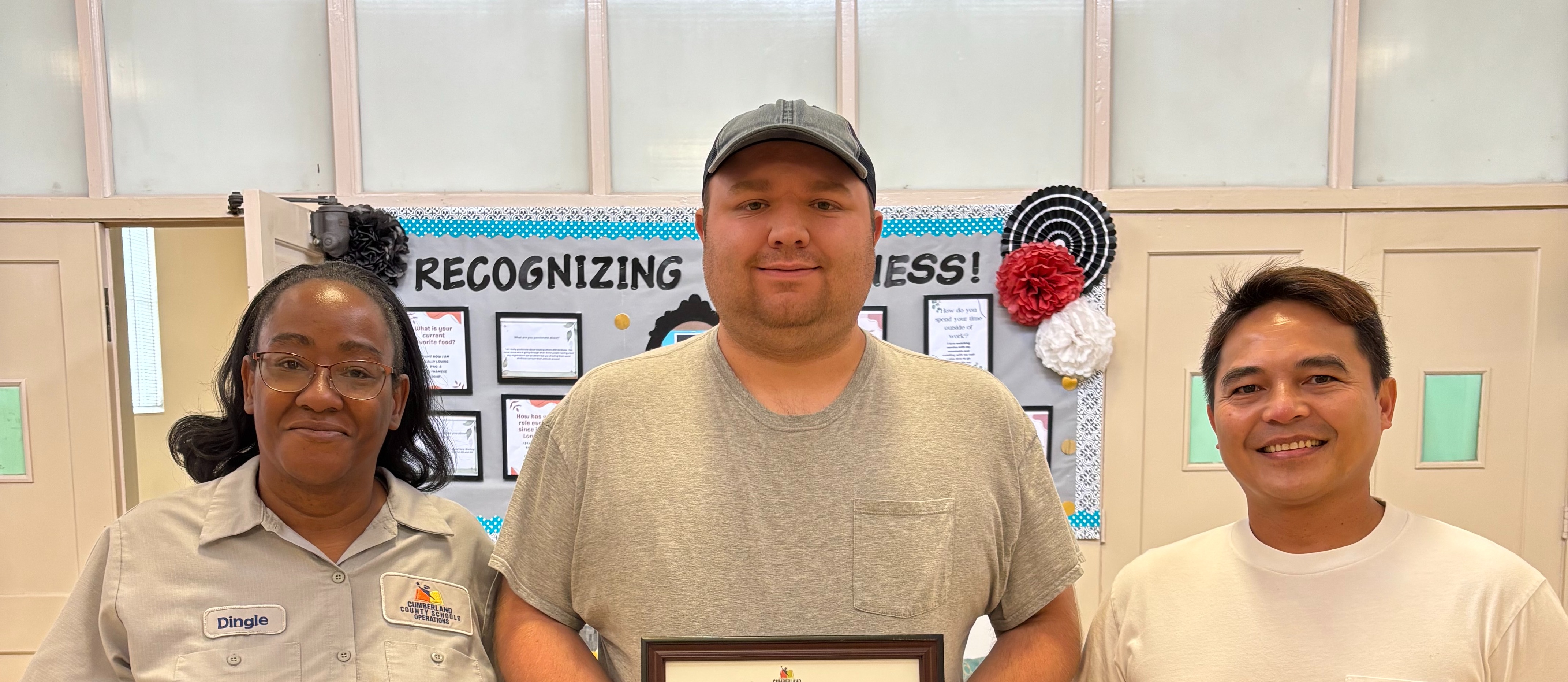 3 custodians standing together holding an award