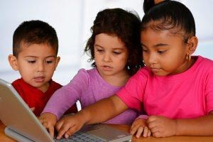 little kids gathered looking at a laptop screen