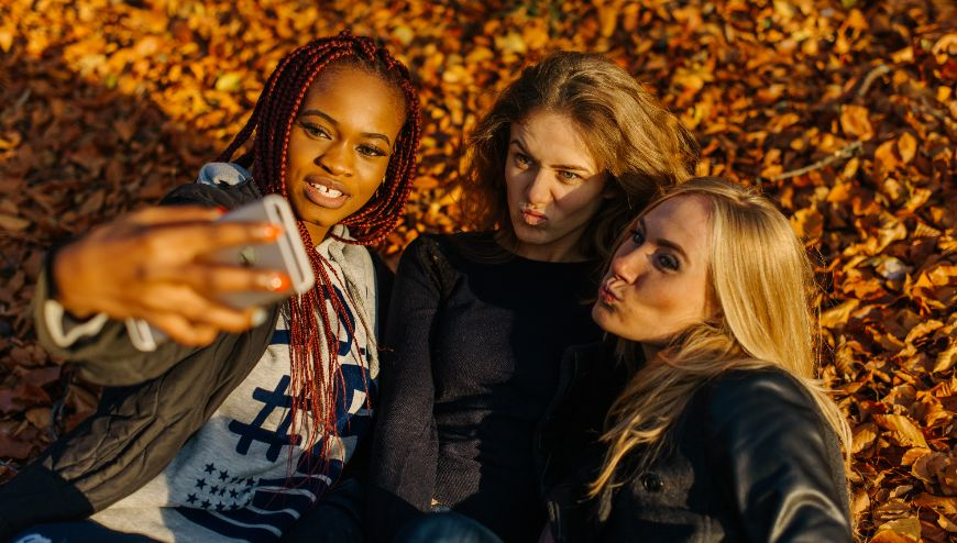 Three girls taking a selfie with leaves as background