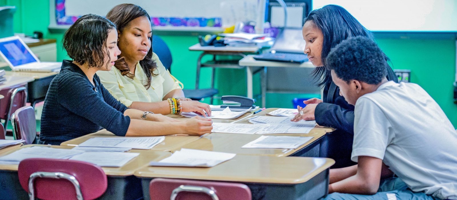 teachers, and a student with parent sitting at a table