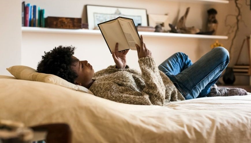 Girl lying on bed reading