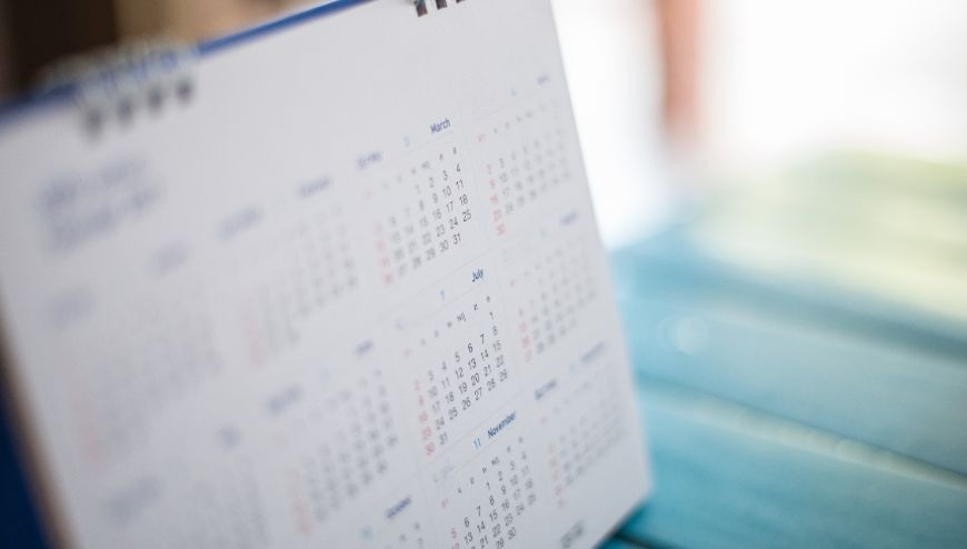 image of a calendar that is blurry sitting on a blue table with a white background.