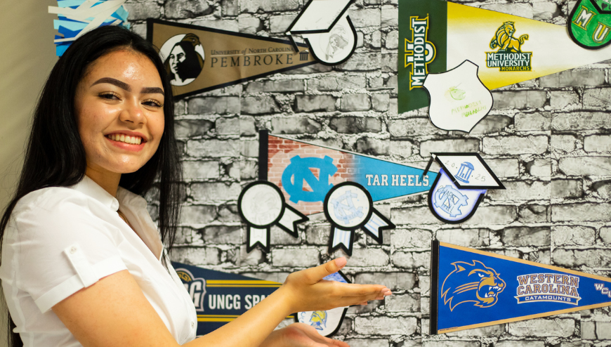 Student pointing to College Flags